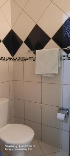 a bathroom with a white toilet and black and white tiles at Pousada Iguana in Canoa Quebrada