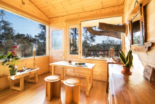 eine Holzhütte mit einem Tisch und 2 Fenstern in der Unterkunft Romantic Tree House in Kato Pavliana