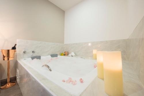 a white bathroom with a tub with a candle at Medellín Vibes Hostel in Medellín