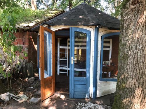 a greenhouse with blue doors next to a tree at Bequemschlafen in Heidenau