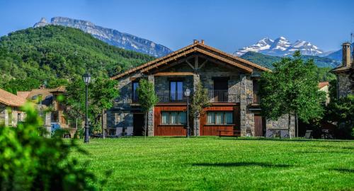 a house with a green lawn in front of a mountain at Casas la Ribera Ordesa in Escalona