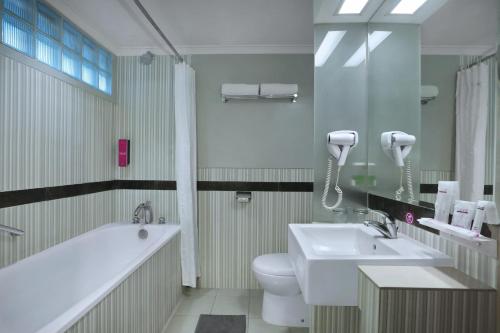 La salle de bains est pourvue d'une baignoire, de toilettes et d'un lavabo. dans l'établissement favehotel Premier Cihampelas, à Bandung