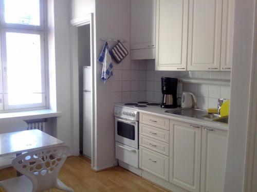 a kitchen with white cabinets and a sink and a stove at Apartments Hotel Rivoli Jardin in Helsinki