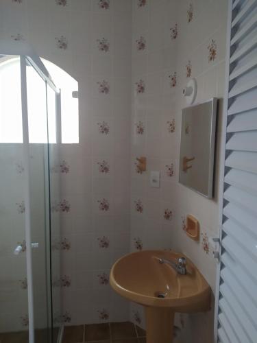 a bathroom with a sink and a glass shower at Hotel Haloha in Peruíbe