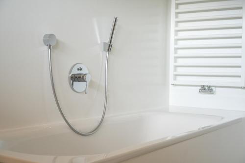 a shower in a white bathroom with a tub at Chalet Tolder in San Candido