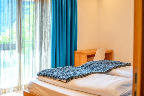 サン・カンディドにあるChalet Tolderの椅子と青いカーテン付きの窓が備わる客室です。