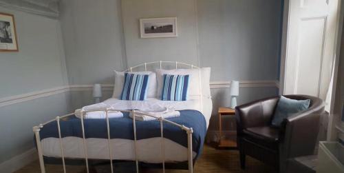 een slaapkamer met een bed met blauwe en witte kussens en een stoel bij The Top House Inn in Lizard