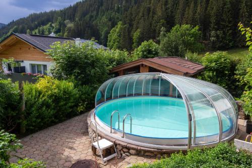 una piscina con una cúpula de cristal frente a una casa en Appartement Krahlehen, en Filzmoos