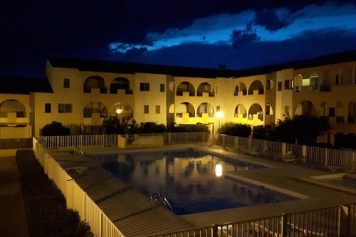 une piscine devant un immeuble la nuit dans l'établissement Studio mezzanine en résidence avec piscine au village, au Barcarès