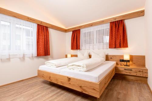 a bedroom with two beds and two windows at Appartement Pension Auhof in Going