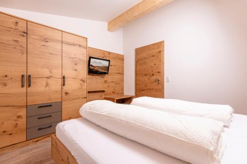 a bedroom with two beds and a tv on the wall at Appartement Pension Auhof in Going