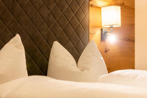 a bed with white pillows and a head board at Appartement Pension Auhof in Going