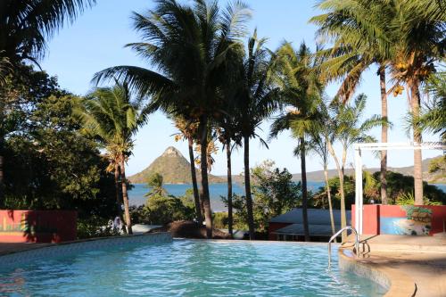 una piscina con palmeras y vistas al océano en Hotel De La Baie en Diego Suarez