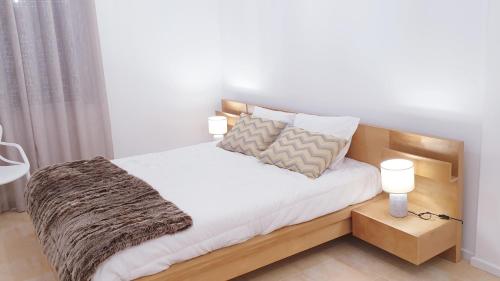 um quarto com uma cama com lençóis brancos e almofadas em TOPO Apartment em Ponta Delgada