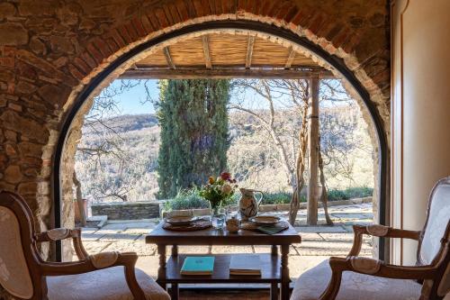 um quarto com uma mesa e uma grande janela em Castello di Volpaia em Radda in Chianti