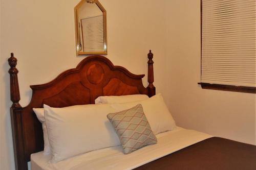 1 cama con cabecero de madera y almohadas blancas en Arhaus 2, en Grand Forks