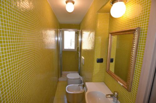 un bagno giallo con un lavandino e uno specchio di Viola apartment, Levanto - 5 Terre a Levanto