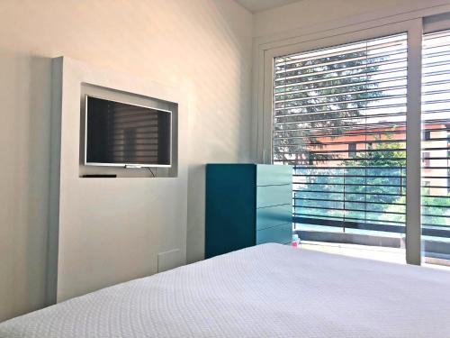 a bedroom with a bed and a tv and a window at Roggia Apartments by Quokka 360 - a stone's throw from Ciani Park in Lugano