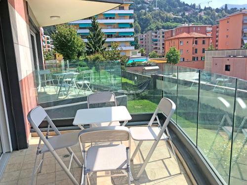 a balcony with white tables and chairs on a building at Roggia Apartments by Quokka 360 - a stone's throw from Ciani Park in Lugano