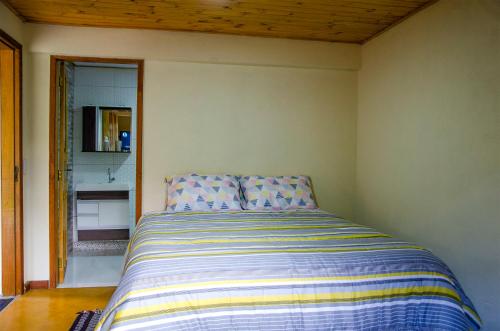 a bedroom with a bed with a striped comforter at Chalé vista da mata in Visconde De Maua