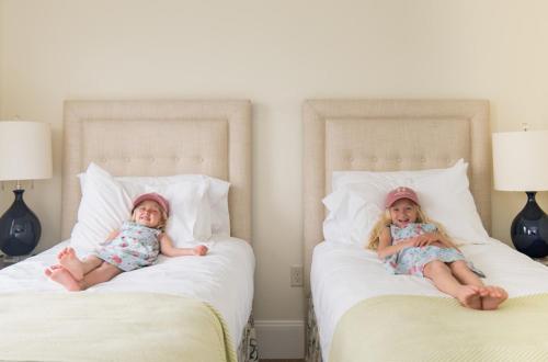 two young girls laying on a bed with pillows at The Nantucket Hotel & Resort in Nantucket