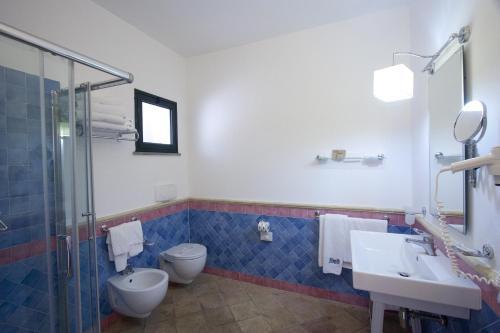 łazienka z toaletą, 2 umywalkami i prysznicem w obiekcie TH Le Castella - Baia degli Dei Village w mieście Le Castella