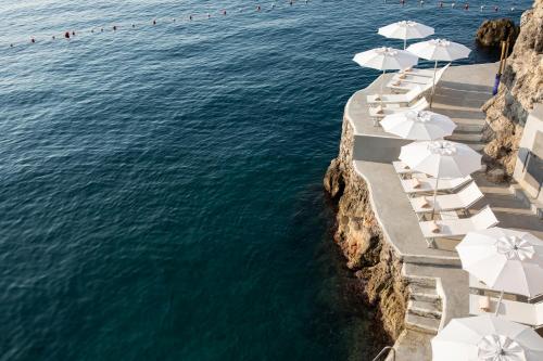 a row of white umbrellas on a beach next to the ocean at Hotel Miramalfi in Amalfi