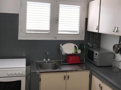 a kitchen with a sink and a microwave at Le Belleplaine in Le Gosier