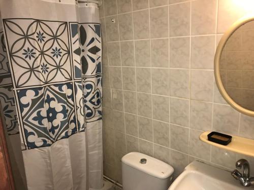 a bathroom with a shower curtain and a toilet at Le Belleplaine in Le Gosier
