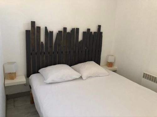 1 cama con 2 almohadas blancas en una habitación en Appartement Vue Mer - Sète, en Sète