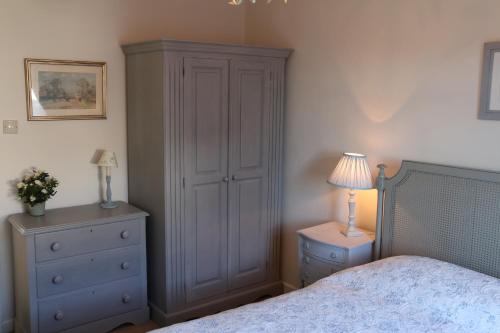 a bedroom with a bed and a cabinet and a lamp at The Boathouse for two, St Davids, Garage Parking in St. Davids