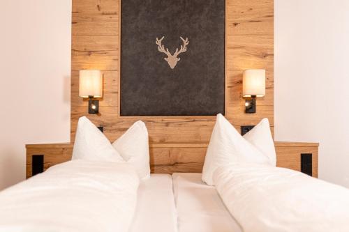a white bed with white pillows and two lights at Appartement Pension Auhof in Going