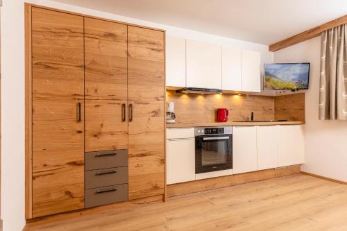 a kitchen with white cabinets and a wooden wall at Appartement Pension Auhof in Going