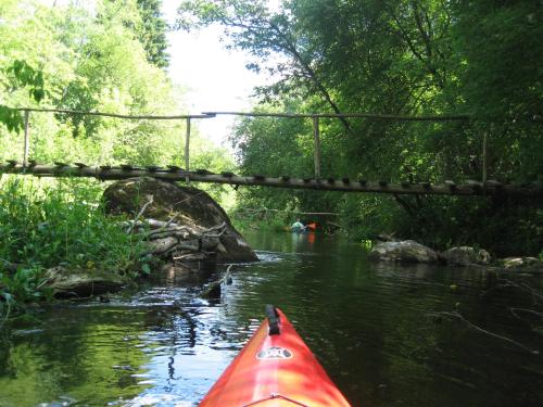 a red kayak on a river with a bridge at Sodyba Pas Drambliuka in Svėdasai