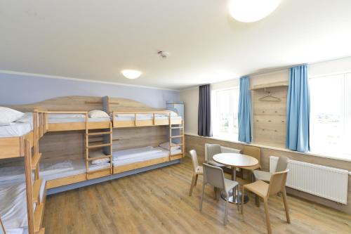 a dorm room with bunk beds and a table and chairs at Haus Klaarstrand in Wenningstedt