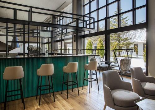 a bar with stools in a room with large windows at Holiday Inn Resort Shinano-Omachi Kuroyon by IHG in Omachi