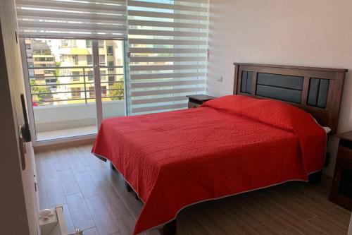 1 dormitorio con cama roja y ventana grande en Arriendo departamento excelente ubicación por día en Viña del Mar