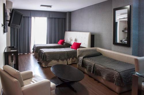 una habitación de hotel con dos camas y un sofá en Ayres Apartments Recoleta - Guido 1980, en Buenos Aires