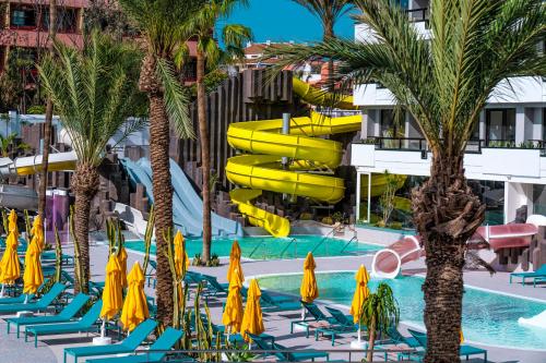 a resort pool with chairs and a water slide at Spring Hotel Bitácora in Playa de las Americas
