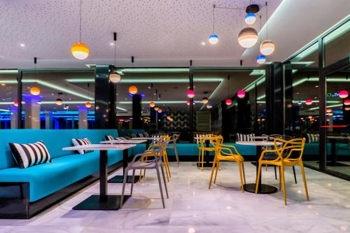 a restaurant with a blue couch and tables and chairs at Spring Hotel Bitácora in Playa de las Americas