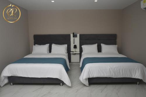 a bedroom with two beds with white and blue sheets at OR HOTEL 94 in Barranquilla