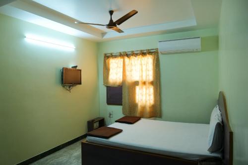 a bedroom with a bed and a ceiling fan at Hotel Vijay in Pollāchi
