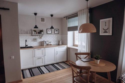 Una cocina con gabinetes blancos y una mesa con sillas. en Teatra street apartment, en Balvi