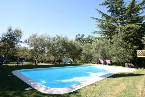 a swimming pool with chairs in the grass at La Stregatta in Fucecchio