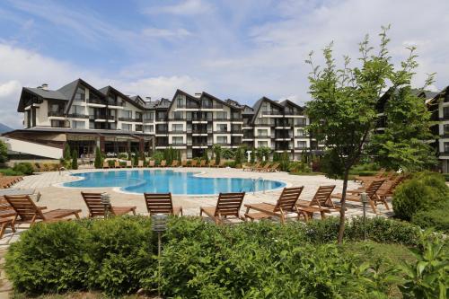un complexe avec une piscine, des chaises et un bâtiment dans l'établissement Aspen Golf and Ski Resort, à Bansko