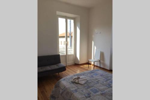 a bedroom with a bed and a chair and a window at Luminoso appartamento in Villa a Stresa in Stresa