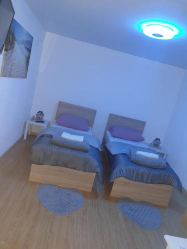 two beds in a room with a blue light at Apartman Ero in Čepin