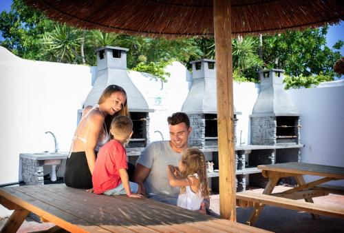 a man and woman and two children sitting on a picnic table at Devesa Gardens in El Saler