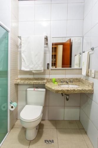 a bathroom with a toilet and a sink and a mirror at VOA Express Inn Hotel Orquídea in Várzea Paulista