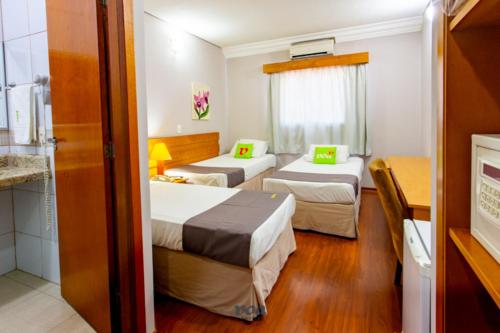 a hotel room with two beds and a kitchen at VOA Express Inn Hotel Orquídea in Várzea Paulista